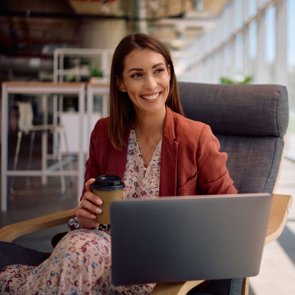 Glimlachende professional met laptop en koffie - SASE secure access service edge in actie